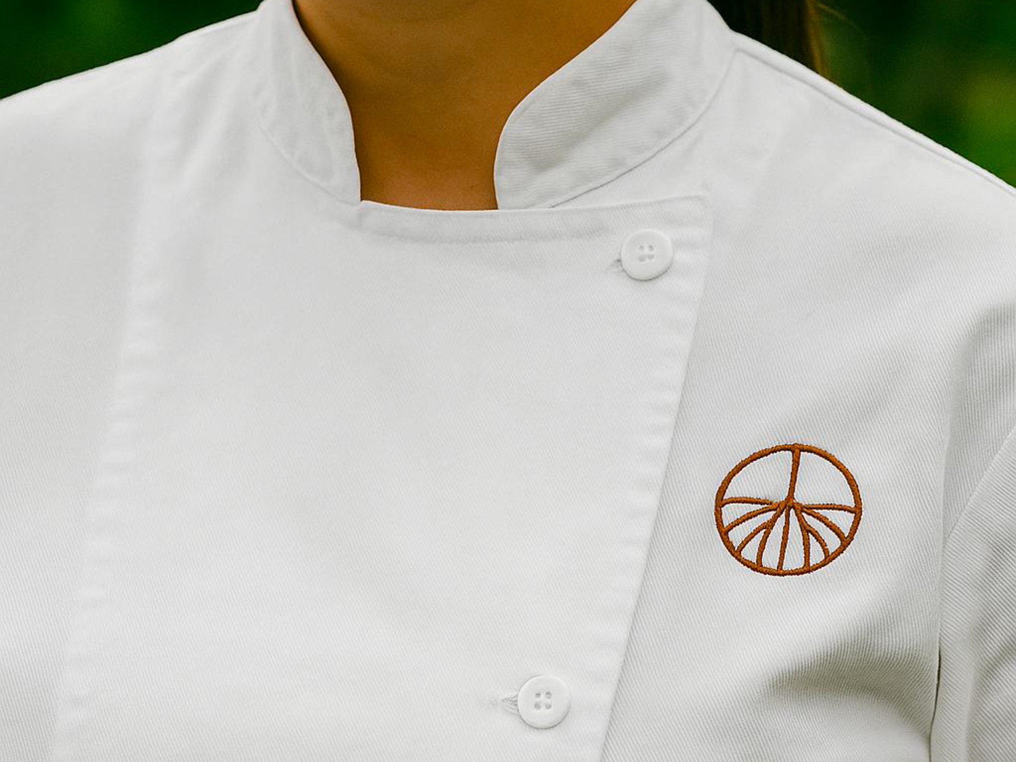 AMAU circular emblem embroidered on a white chef jacket